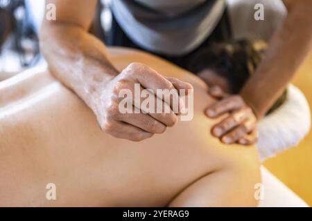 Ein starker männlicher Massagetherapeut, der einem Mann eine tiefe Gewebemassage gibt. Konzepte der Physiotherapie und der Chiropraktik Stockfoto