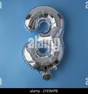 3 drei metallische Ballons isoliert auf blauem Hintergrund. Grußkarte Silberfolie Ballonnummer Happy Birthday Holiday Konzept. Kopierbereich für Text. Ce Stockfoto