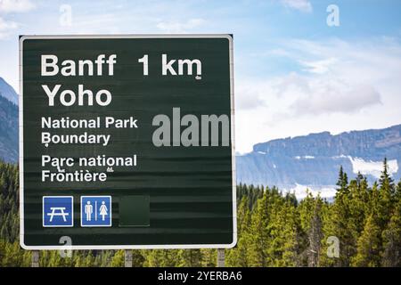 Kanadische zwei Sprachen Französisch und Englisch Informationen Straße grüne Schilder, 1 km von Banff, Yoho National Park, mit Symbolen, Alberta, Kanada Stockfoto