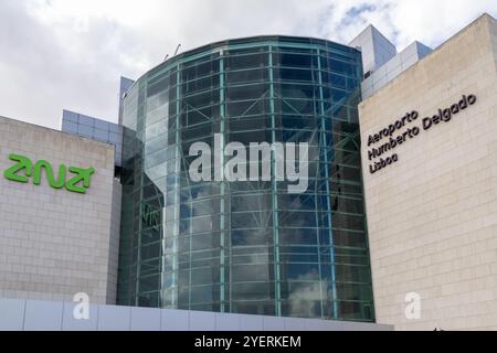 Moderne Architektur des Flughafens lissabon mit geschwungener Glasfassade, die den Himmel reflektiert, und ana-Logo Stockfoto