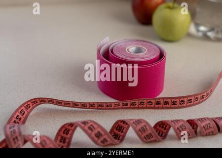 Pinkfarbenes kinesio-Klebeband mit einem Maßband auf weißem Hintergrund Stockfoto