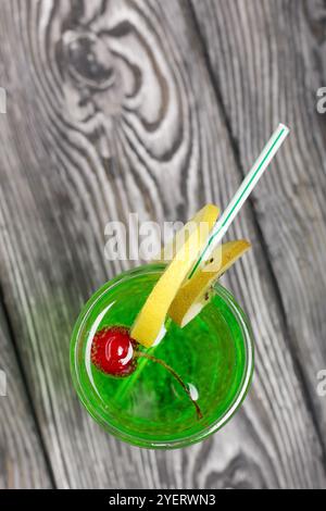 Grüne Limonade im Glas. Kirsche schwimmt darin. Garniert mit einer Zitronenscheibe. Mit einem Strohhalm für einen Cocktail. Stockfoto