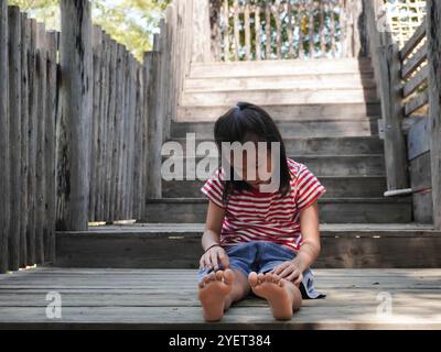 Ein junges Mädchen hat sich beim Spielen auf einem Spielplatz das Knie verletzt. Das verletzte Knie des Kindes. Stockfoto