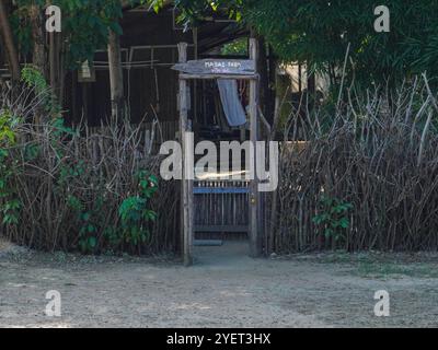 Rustikaler Zaun aus Ästen und Holzpfosten mit einem kleinen Tor, das zum Eingang zu einem Mini Zoo führt. Stockfoto