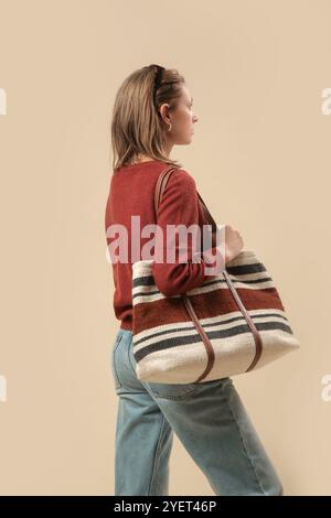 Serie von Studiofotos von Frauen im klassischen Herbst-Freizeitoutfit – blaue Jeans, brauner Pullover, Sonnenbrille und große Tragetasche. Stockfoto
