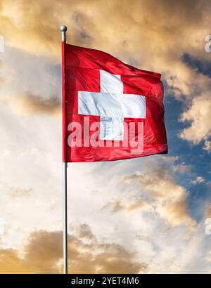 Die Schweizer Flagge winkt gegen den Sonnenunterganghimmel Stockfoto