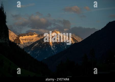 Die untergehende Sonne erleuchtet einen schneebedeckten Gipfel in den österreichischen Alpen. Stockfoto