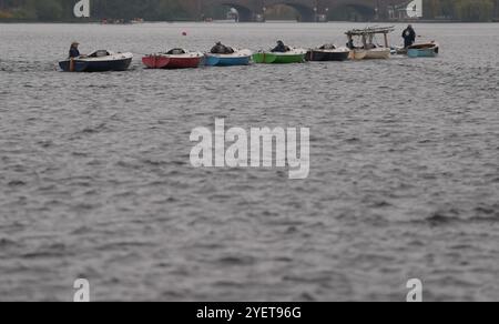 Hamburg, Deutschland. November 2024. Segelboote werden bei bewölktem Herbstwetter von einem Motorboot über die Außenalster gezogen. Quelle: Marcus Brandt/dpa/Alamy Live News Stockfoto