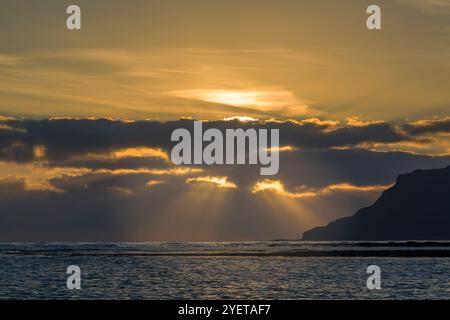 Sonnenaufgang hinter zerbrochenen Wolken mit Sonnenstrahlen, die durchbrechen. Blick von Robin Hood's Bay in Richtung Ravenscar Stockfoto