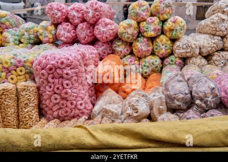 Kleine Tüten mit künstlich fruchtig gewürzten, gesüßten Maispuffs auf einem Tisch am Stand eines Straßenverkäufers in Argentinien. Ungesunder Snack Stockfoto