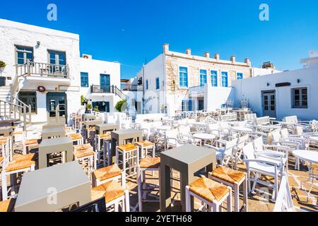 Tische und Stühle im Freien im traditionellen griechischen Café. Typisch griechische Taverne im Hafen von Naoussa, Insel Paros, Griechenland Stockfoto