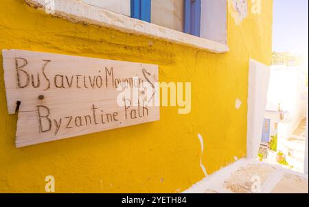 Holzschild des Byzantine Path auf der gelben Seite des Gebäudes in Lefkes, Griechenland Stockfoto