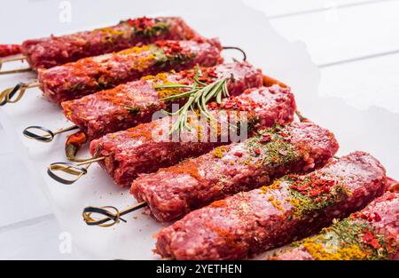 Roher Kebab mit Gewürzen auf einem weißen Tisch Stockfoto