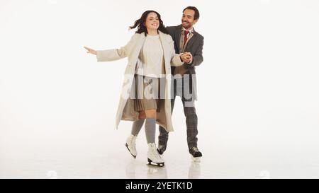 Glückliches Paar kleidete sich warm und stilvoll Winterkleidung, lachte und hielt Hände, während sie zusammen Schlittschuh laufen. Fröhlicher Wintermoment Stockfoto