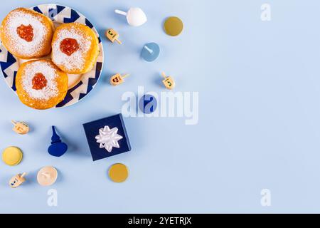 Traditionelle Leckereien, Symbole des Feiertags von Hanukka auf blauem Hintergrund. Donuts, Dreidels, Schokoladenmünzen für Kinder. Draufsicht. Ein Kopierbereich. Stockfoto