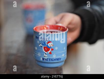 Hamburg, Deutschland. November 2024. Ein Besucher greift auf dem Weihnachtsmarkt Wandsbeker Winterzauber nach einer Tasse Glühwein. Quelle: Marcus Brandt/dpa/Alamy Live News Stockfoto