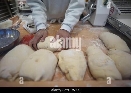 Hamburg, Deutschland. November 2024. Ein Mitarbeiter kntet den Teig für Schmalzkuchen an einem Stand auf dem Wandsbeker Winterzauber Weihnachtsmarkt. Quelle: Marcus Brandt/dpa/Alamy Live News Stockfoto