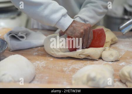 Hamburg, Deutschland. November 2024. Ein Mitarbeiter kntet den Teig für Schmalzkuchen an einem Stand auf dem Wandsbeker Winterzauber Weihnachtsmarkt. Quelle: Marcus Brandt/dpa/Alamy Live News Stockfoto