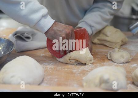 Hamburg, Deutschland. November 2024. Ein Mitarbeiter kntet den Teig für Schmalzkuchen an einem Stand auf dem Wandsbeker Winterzauber Weihnachtsmarkt. Quelle: Marcus Brandt/dpa/Alamy Live News Stockfoto