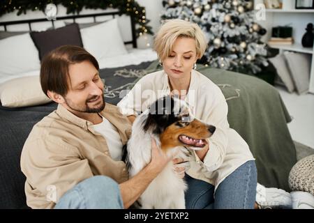 Ein Paar genießt während der Festtage eine gute Zeit zu Hause mit seinem verspielten Hund. Stockfoto