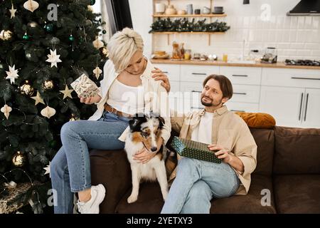 Ein Paar teilt einen wunderbaren Moment auf der Couch, umgeben von Feiertagsstimmung und einem Haustier. Stockfoto