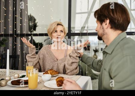 Ein Paar teilt sich ein warmes Frühstück zu Hause, gefüllt mit Lächeln und lebhaften Gesprächen. Stockfoto