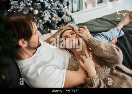 Ein liebevolles Paar genießt eine warme Umarmung, während es sich zu Hause in der Weihnachtsdekoration entspannt. Stockfoto