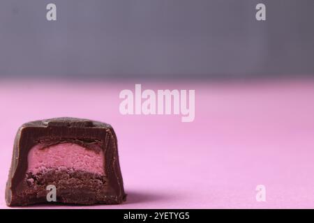 Ein Stück Süßigkeiten auf rosa Hintergrund mit Beerenfüllung: Erdbeere, Himbeere, Mango. Stockfoto