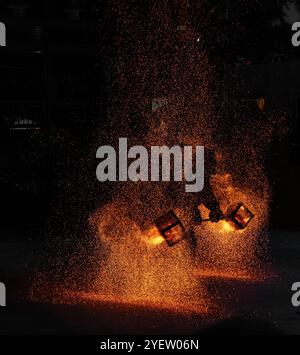 Feuertopf-Performance, bei der ein Künstler ein feuriges Eisennetz mit brennender Kohle manipuliert und einen atemberaubenden Funkenregen erzeugt Stockfoto