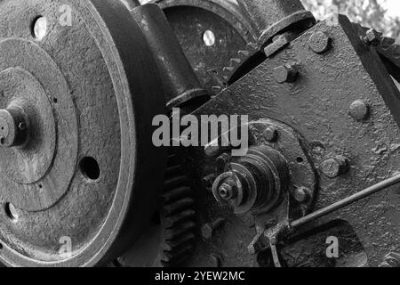 Zahnräder und andere Teile von Vintage-schwarzen Industriemaschinen, Nahaufnahme Schwarzweiß-Foto mit selektivem Fokus, abstrakter Hintergrund der Schwerindustrie Stockfoto