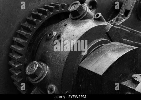 Massive schwarze Zahnräder und andere Teile von Vintage-Industriemaschinen, Nahaufnahme Schwarzweiß-Foto mit selektivem Fokus, abstrakter Hintergrund der Schwerindustrie Stockfoto