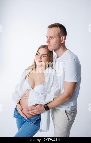 Ein Mann umarmt eine schwangere Frau und streichelt ihren Bauch, ein glückliches junges Paar ist schwanger. Stockfoto