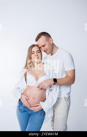 Ein Mann umarmt eine schwangere Frau und streichelt ihren Bauch, ein glückliches junges Paar ist schwanger. Stockfoto