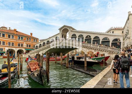 Venedig, Vento – IT – 14. Oktober 2024 die berühmte Rialto-Brücke führt über den Canale Grande von Venedig, mit Gondeln im Vordergrund und Touristen, die einen Spaziergang machen Stockfoto