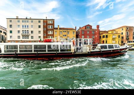 Venedig, Vento – IT – 13. Okt. 2024 Ein Vaporetto stürzt den Kanal hinunter, sein schlankes, flaches Profil schneidet durch das Wasser und erzeugt plätschernde Wellen. Durchläufe Stockfoto