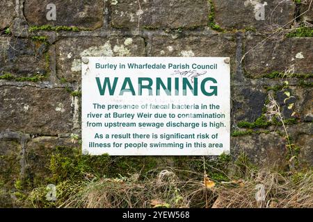 Abwasser-Ableitung in den River Wharfe Warnschild am Burley im Wharfedale Weir in der Nähe von Ilkley mit Graffiti mit der Aufschrift „Shame on you Yorkshire Water“ Großbritannien Stockfoto