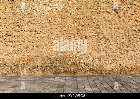 Eine rustikale Steinmauer trifft auf einen gepflasterten Bürgersteig und schafft eine kontrastierende Textur Stockfoto