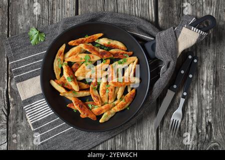Schupfnudeln, Fingernudel, deutsche Kartoffeldicknudeln, Knödel in einer Pfanne auf rustikalem Holztisch mit Besteck, horizontale Sicht von oben, fla Stockfoto