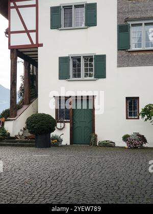 Beige Hausfassade mit grüner Tür und Fensterläden. Haus auf einer Straße in der Altstadt. Stockfoto