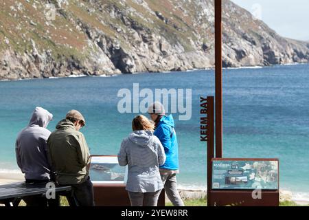 Touristen an einem windigen Tag am wilden atlantic Way Discovery Point und Banshees von Inisheerin Information Point Keem Beach Achill Island, County Mayo, r Stockfoto