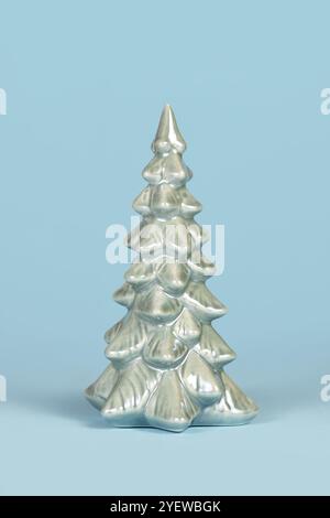 Einzelner hellgrüner Keramik-Weihnachtsbaum auf pastellblauem Hintergrund Stockfoto