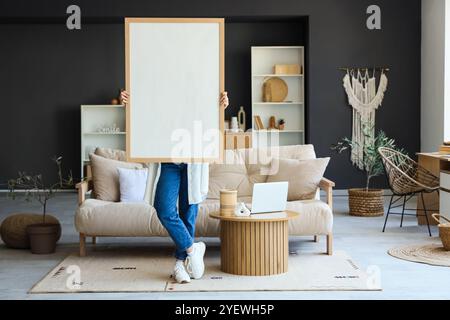 Junge Frau mit großem Rahmen im Wohnzimmer Stockfoto