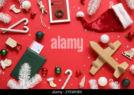 Rahmen aus Spielzeug, Holzflugzeug und Reisepass auf rotem Hintergrund. Weihnachtsferienkonzept Stockfoto