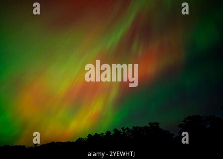 Leuchtende rote und grüne Auroras (Nordlichter) bemalen den Nachthimmel und schaffen eine faszinierende und surreale Atmosphäre über der Grand Traverse Bay, Michigan, Stockfoto