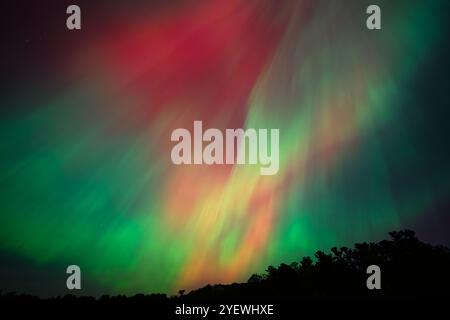 Leuchtende rote und grüne Auroras (Nordlichter) bemalen den Nachthimmel und schaffen eine faszinierende und surreale Atmosphäre über der Grand Traverse Bay, Michigan, Stockfoto