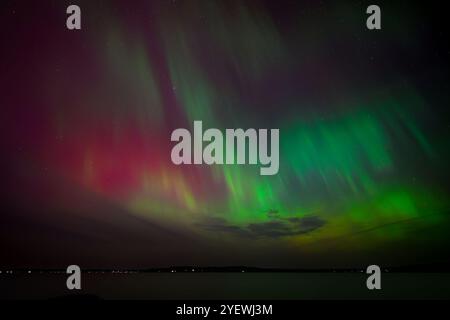 Leuchtende rote und grüne Auroras (Nordlichter) bemalen den Nachthimmel und schaffen eine faszinierende und surreale Atmosphäre über der Grand Traverse Bay, Michigan, Stockfoto