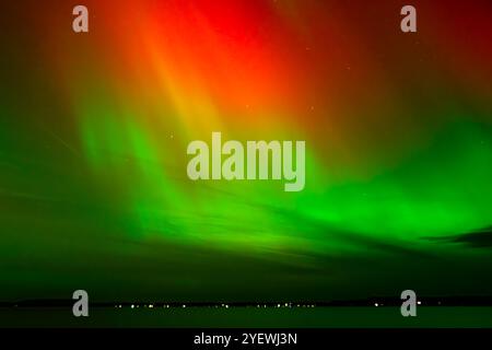 Leuchtende rote und grüne Auroras (Nordlichter) bemalen den Nachthimmel und schaffen eine faszinierende und surreale Atmosphäre über der Grand Traverse Bay, Michigan, Stockfoto