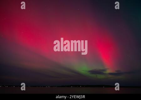 Leuchtende rote und grüne Auroras (Nordlichter) bemalen den Nachthimmel und schaffen eine faszinierende und surreale Atmosphäre über der Grand Traverse Bay, Michigan, Stockfoto