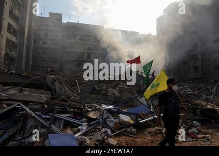 Beirut, Beirut, Libanon. November 2024. Ein pro-iranischer Hisbollah-Unterstützer trägt die Parteiflagge vor Trümmern flacher Gebäude, die von israelischen Luftangriffen auf den südlichen Vorort Beiruts, einem Brutgebiet der Gruppe, angegriffen wurden. (Kreditbild: © Marwan Naamani/ZUMA Press Wire) NUR REDAKTIONELLE VERWENDUNG! Nicht für kommerzielle ZWECKE! Stockfoto