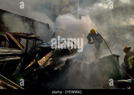 Beirut, Beirut, Libanon. November 2024. Zivilschutzarbeiter sind in Rauch verwickelt, wenn sie versuchen, das Feuer von Autos und zerstörten Gebäuden abzuschütteln, die von israelischen Luftangriffen auf den südlichen Vorort Beiruts, einer Brutstätte der pro-iranischen Hisbollah-Partei, angegriffen wurden. (Kreditbild: © Marwan Naamani/ZUMA Press Wire) NUR REDAKTIONELLE VERWENDUNG! Nicht für kommerzielle ZWECKE! Stockfoto